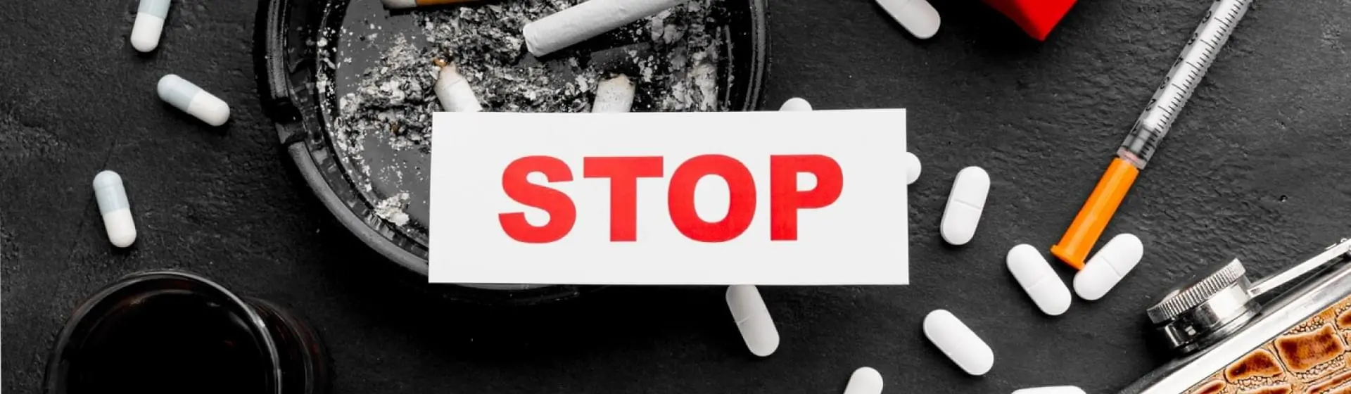 The word stop with pills and cigarettes on the background.