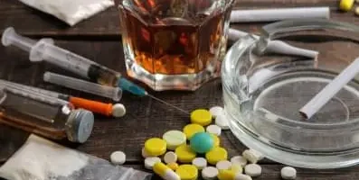 pills on table next to a glass of liquor.