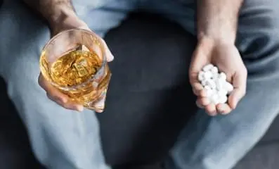 Hand holding Benzodiazepines with alcohol.