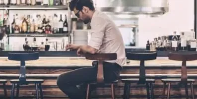 Man at bar staring down.