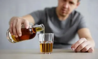 person pouring alcohol into glass.