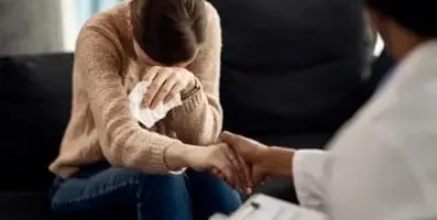 Woman crying with doctor holding her hand.
