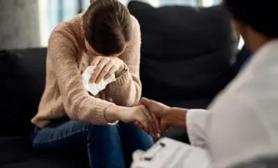 Woman crying with doctor holding her hand.