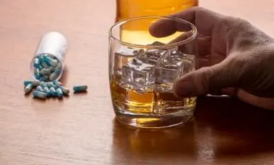 Pills on table next to alcohol.
