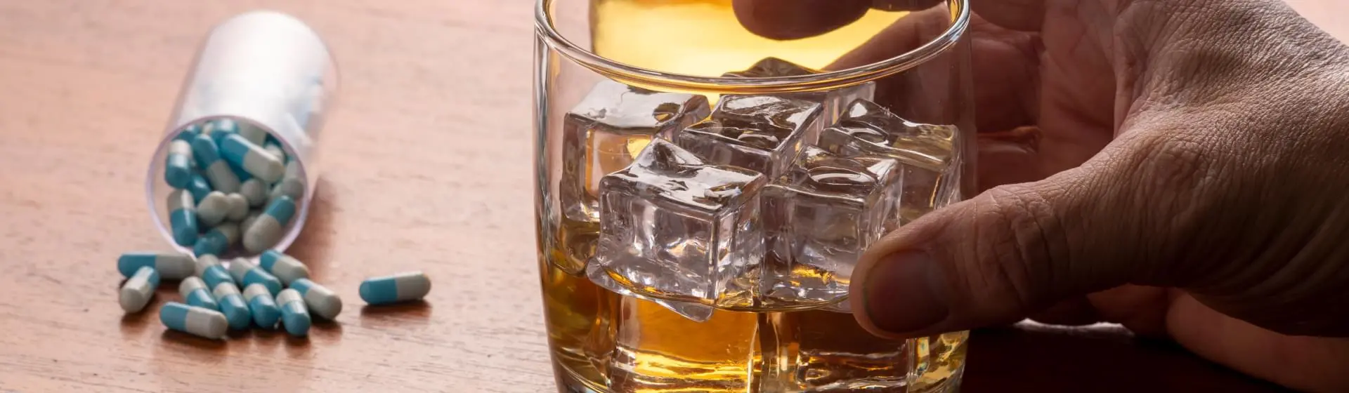 Pills on table next to alcohol.