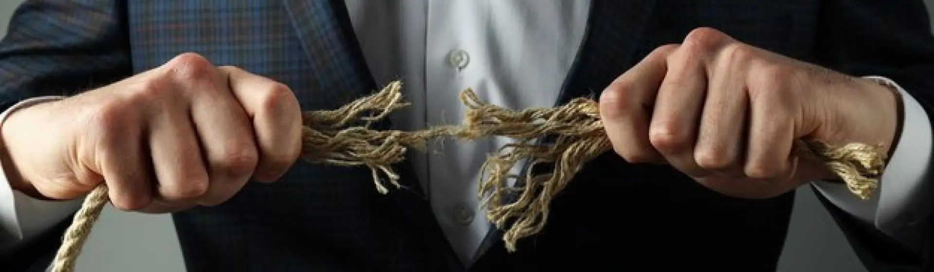 Man pulling apart ropes ripping it.