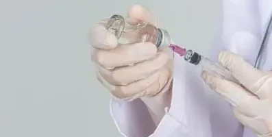 Doctor inserting syringe in bottle.