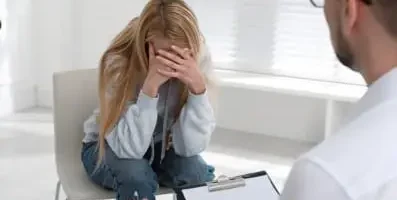 Woman curled up in a chair. Comprehensive treatment plans, including inpatient and outpatient care, are essential for addressing drug abuse.