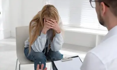 Woman curled up in a chair. Comprehensive treatment plans, including inpatient and outpatient care, are essential for addressing drug abuse.