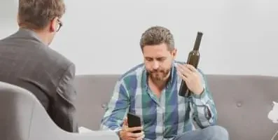 A man at therapy holding a wine bottle