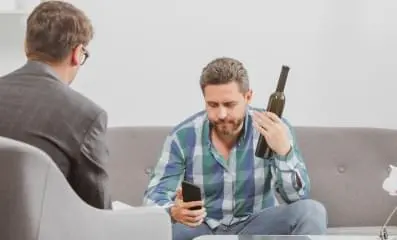 A man at therapy holding a wine bottle