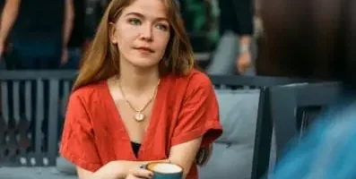 A woman daydreaming holding a cup of coffee.