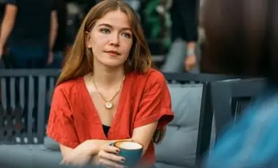A woman daydreaming holding a cup of coffee.