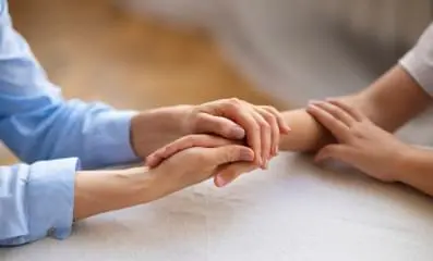 A person holding another person hand in support