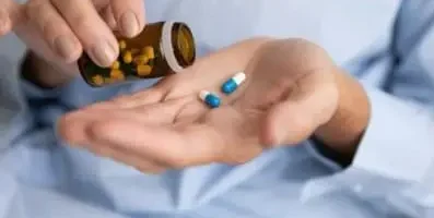 A hand pouring pills unto the other.