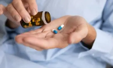 A hand pouring pills unto the other.