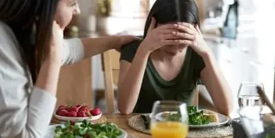 Woman at dinner not eating because of eating disorder.