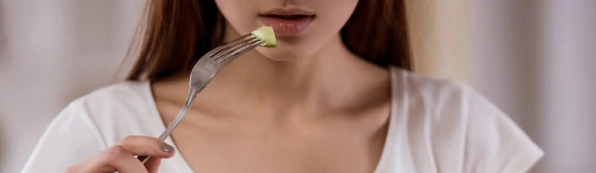 A woman eating one cucumber.