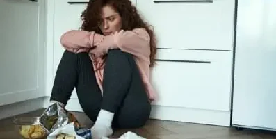 Frustrated woman sitting on the ground along with her food not eating it.