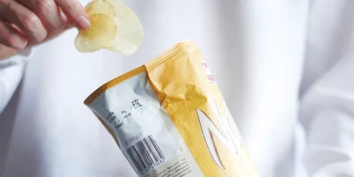 man grabbing potato chips out of a bag of chips