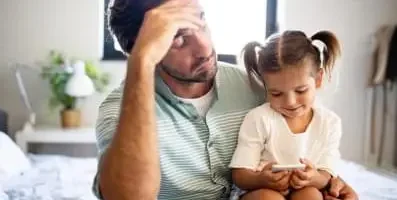 A father sitting down with his daughter on his lap.