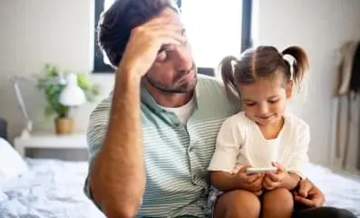 A father sitting down with his daughter on his lap.