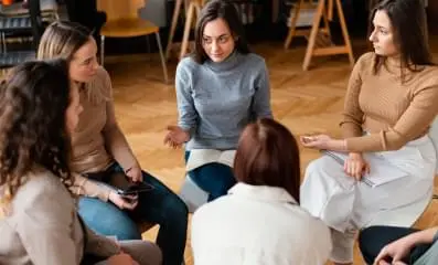 Image of women sitting in a circle during a support group meeting.