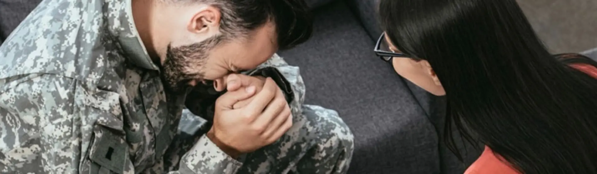 Man in army fatigues, crying with a therapist.