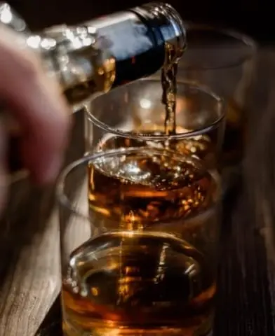Hand pouring alcohol in glass.