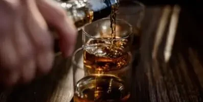 Hand pouring alcohol in glass.