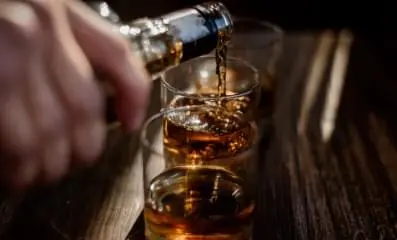 Hand pouring alcohol in glass.