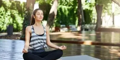 Woman meditating by a pool.