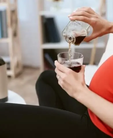 Pregnant woman holding a glass of red wine.