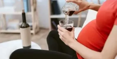 Pregnant woman holding a glass of red wine.