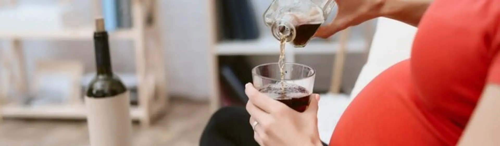 Pregnant woman holding a glass of red wine.