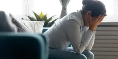 Profile of a woman sitting on a couch with her head in her hands