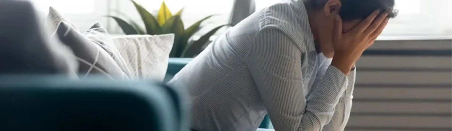 Profile of a woman sitting on a couch with her head in her hands