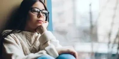 Young woman sitting and gazing out the window.