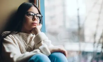 Young woman sitting and gazing out the window.