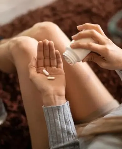 Woman putting pills in her hand from the bottle. Synthetic opioids are lab-manufactured painkillers.