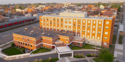 Aerial view of the Indiana Center for Recovery facility in South Bend, showing the large brick building surrounded by landscaped grounds and city streets during sunset.