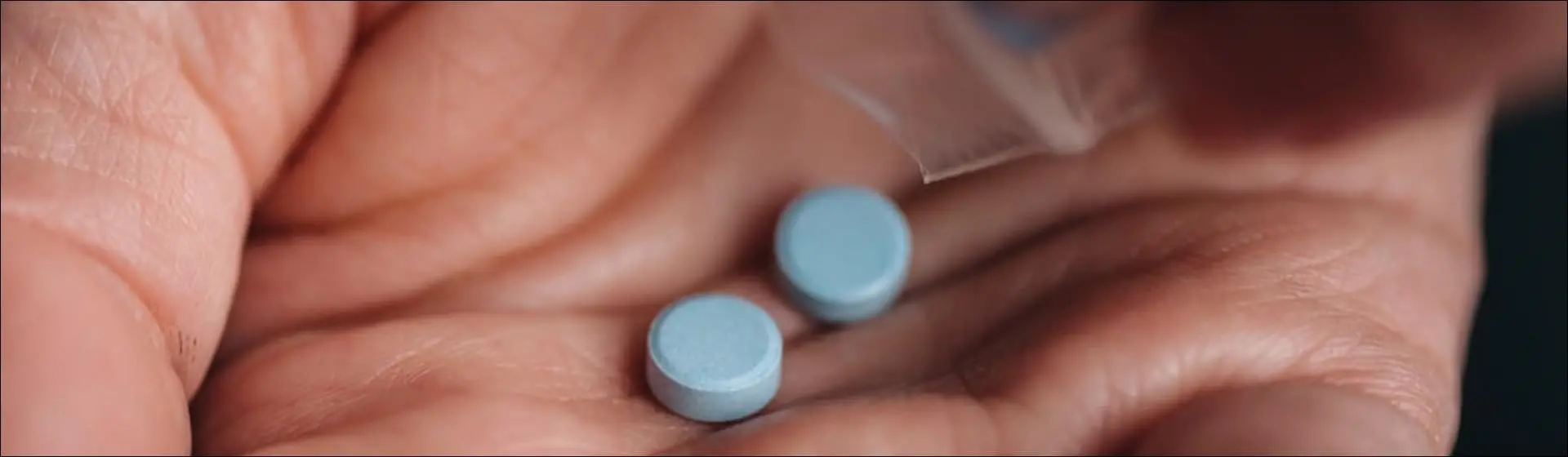 Two blue pills in hand. Klonopin addiction can lead to physical dependence and withdrawal symptoms when use is stopped.