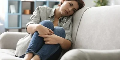 Depressed woman sitting on couch.