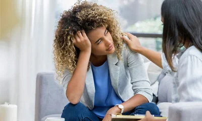 A person sitting alone with head in hands, representing mental health concerns and seeking support.
