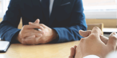 A doctor talking to a patient in a clinical setting with both parties with clasped hadns