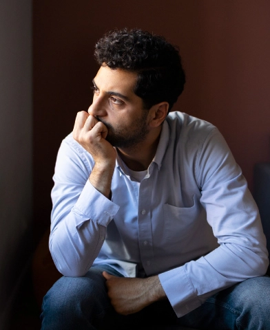 Sad man looking at of a window while he rests his chin on his palm