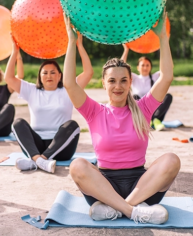 A group of women in a group therapy session, all holding a ball over their heads