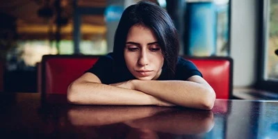 saddened woman with her arms crossed and her chin resting on it