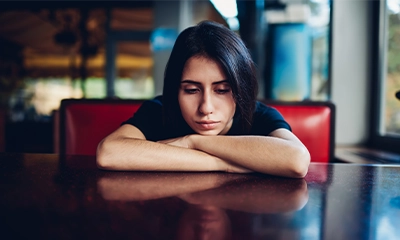 saddened woman with her arms crossed and her chin resting on it