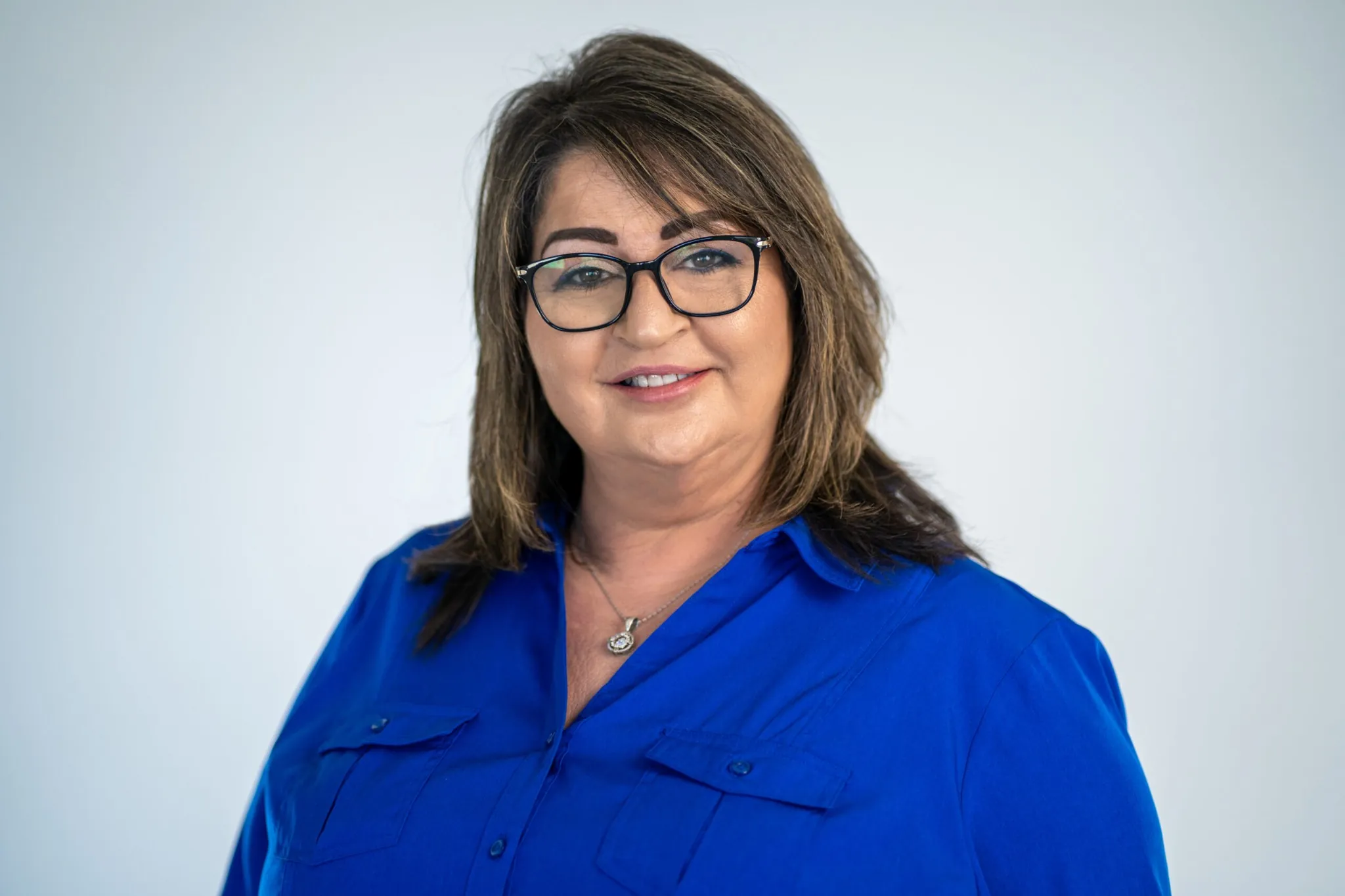 Lucy Weiss professional headshot wearing a blue blouse against a neutral background